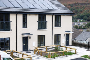 New homes with cream exteriors, two black front doors, windows showing ground floor and first floor, as well as the view over the Rhonnda valley.